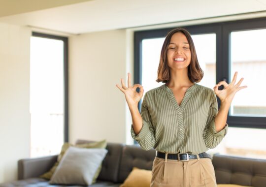 Imagem de uma mulher relaxando dentro da sala de sua casa.